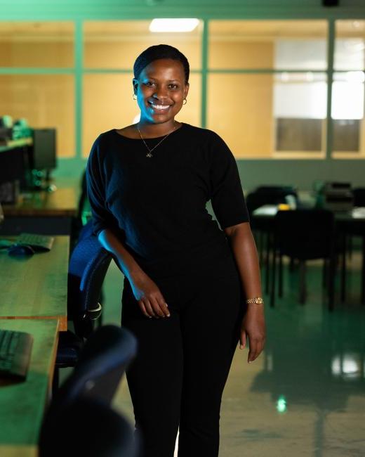 Kettering computer engineering student Tanisha Frances stands in an empty classroom next to desks with computers