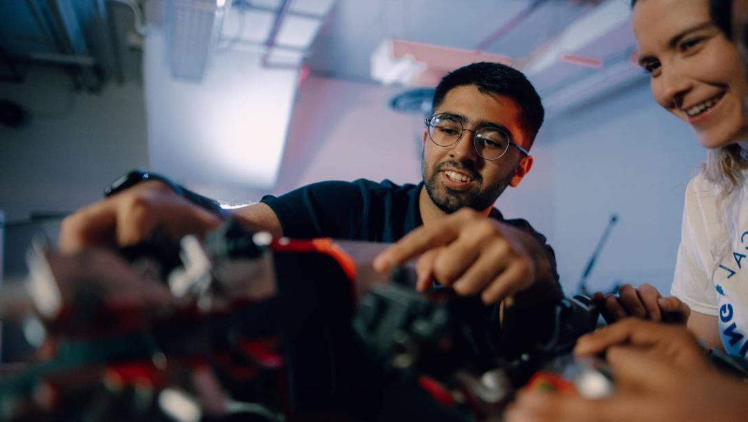 Three Kettering mechanical engineering students inspect car parts in the Car Lab.